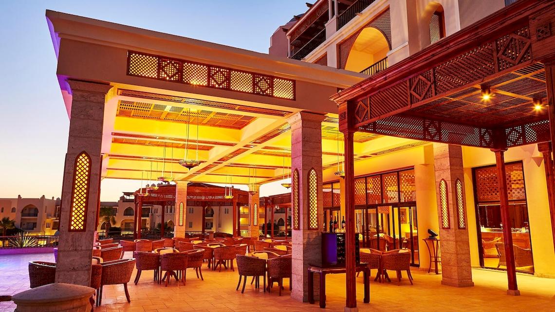 Außenbereich des Kempinski Hotel Soma Bay mit abendlicher Beleuchtung und rustikalen Möbeln.