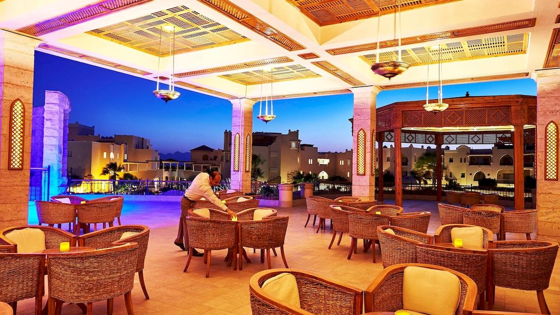 Terrasse des Kempinski Hotel Soma Bay mit abendlicher Beleuchtung und Blick auf die Stadt.