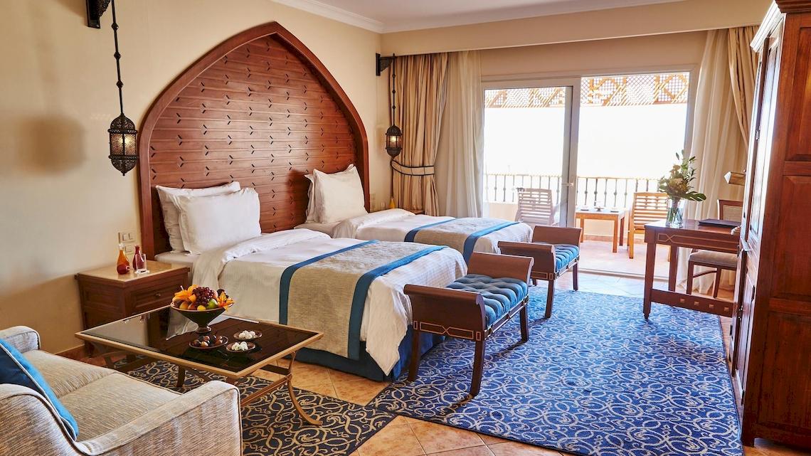 Suite-Zimmer im Kempinski Hotel Soma Bay mit zwei Betten, einem Wohnzimmerbereich und einem Balkon.