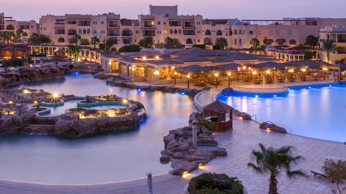 Luftaufnahme des Kempinski Hotels Soma Bay mit beleuchtetem Pool und umgebenden Gebäuden.