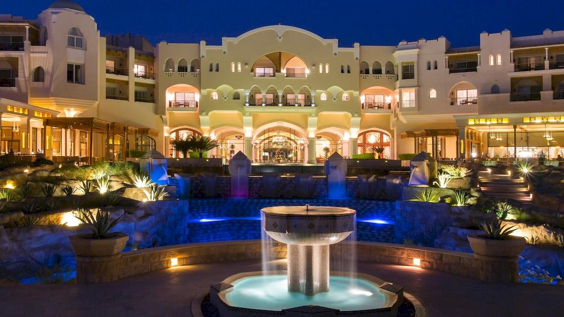 Haupteingang des Kempinski Hotel Soma Bay bei Nacht mit Wasserbrunnen und Beleuchtung.