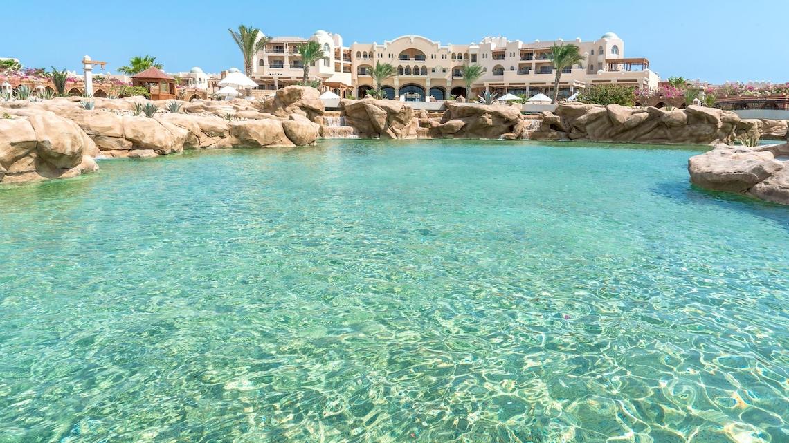 Ein kristallklarer Pool im Kempinski Hotel Soma Bay, umgeben von Felsen und Wasserfällen.