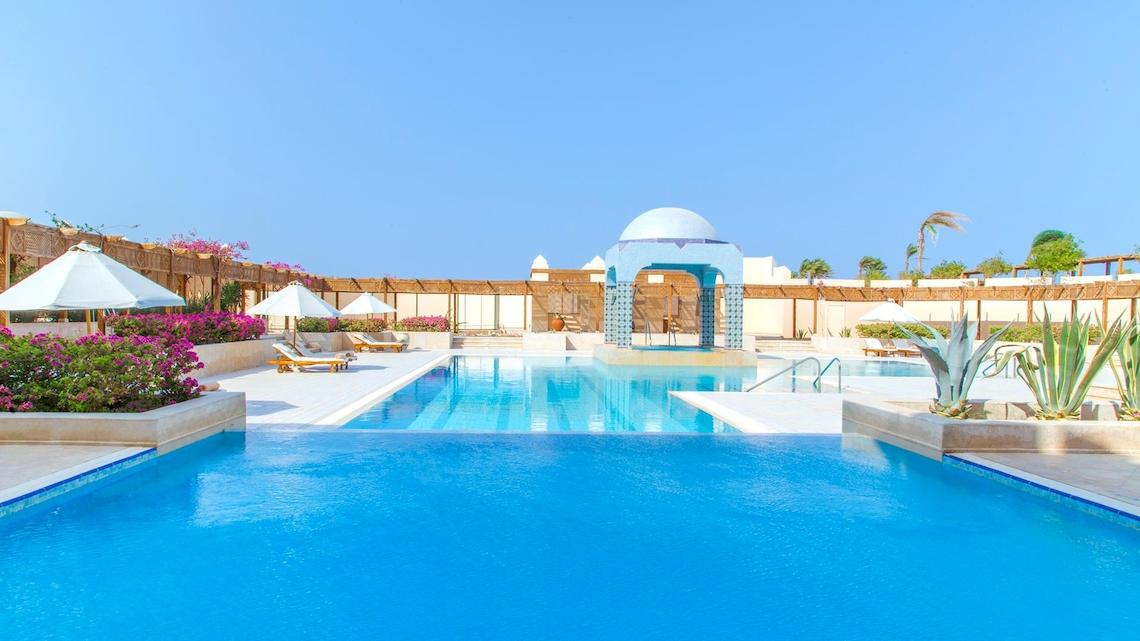 Ein Swimmingpool im Kempinski Hotel Soma Bay mit Sonnenliegen und Sonnenschirmen.