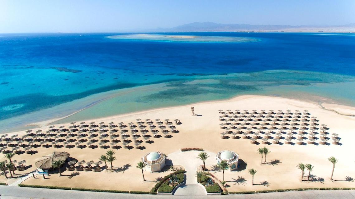 Luftaufnahme des Kempinski Hotel Soma Bay Strands mit vielen Sonnenschirmen und Palmen
