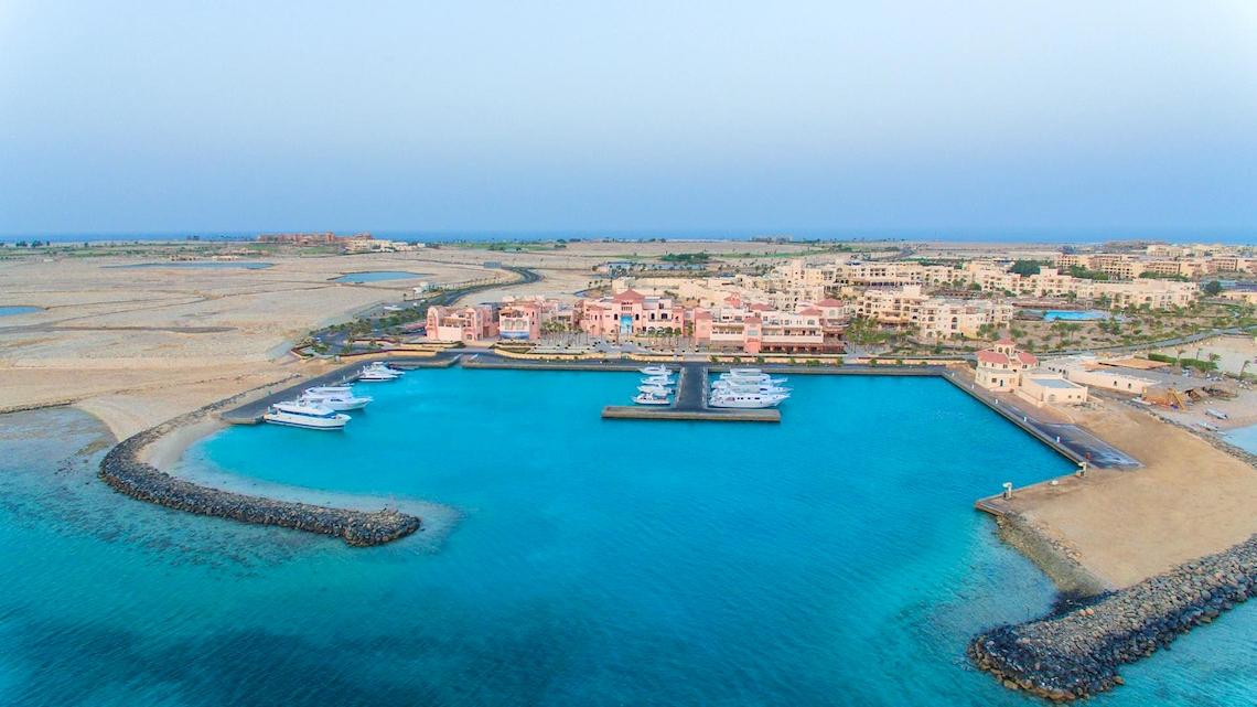 Luftaufnahme des Kempinski Hotel Soma Bay Hafens mit verankerten Booten und umliegender Landschaft.