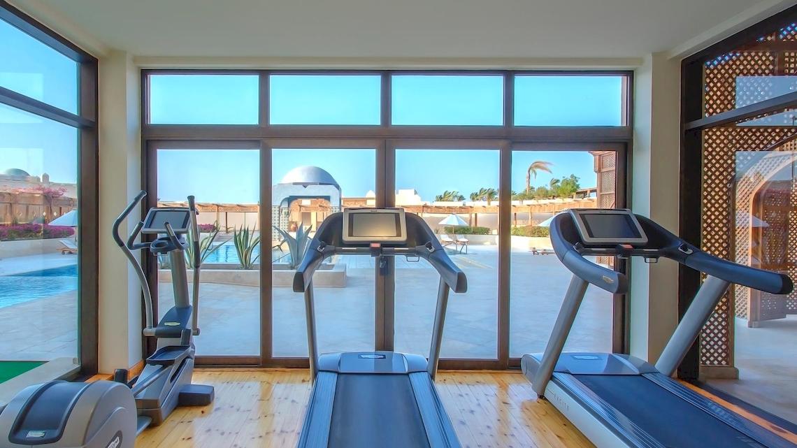 Fitnessraum im Kempinski Hotel Soma Bay mit Blick auf den Pool und das Außengelände.