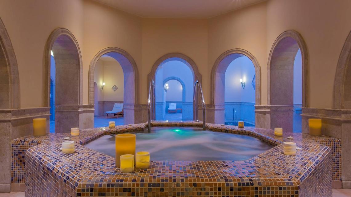 Wellnessbereich im Kempinski Hotel Soma Bay mit einem großen Whirlpool und farbigen Kacheln.