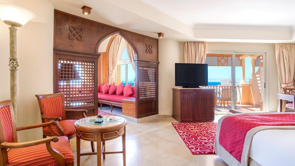Zimmer im Kempinski Hotel Soma Bay mit Balkon, Fernseher, Sofa und Meerblick.