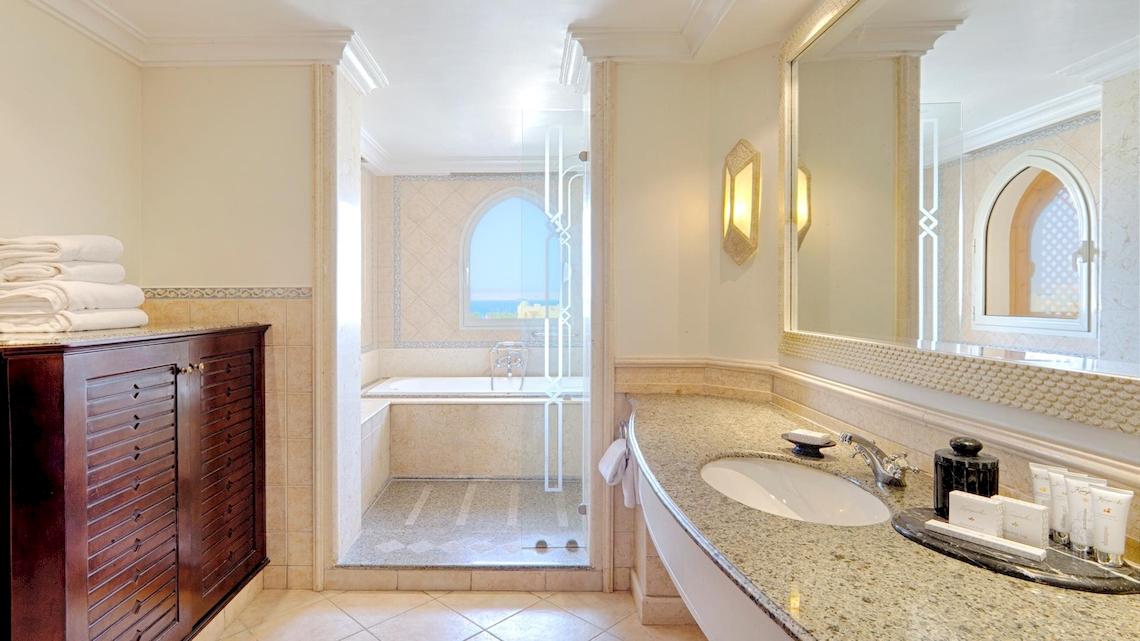 Badezimmer im Kempinski Hotel Soma Bay mit Badewanne, Dusche, Waschbecken und Spiegel.