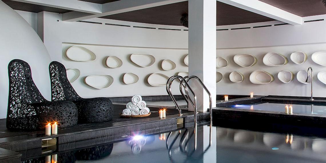 Spa-Bereich im Myconian Utopia Resort mit Innenpool, Kerzen und weißen Wänden.