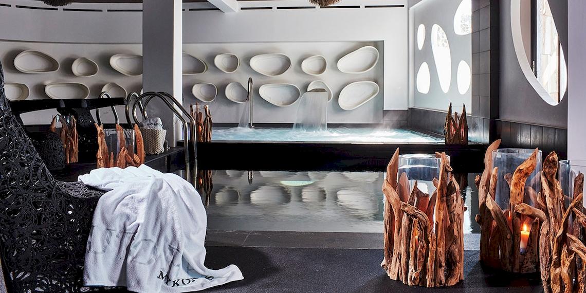 Innenansicht des Spa-Bereichs im Myconian Utopia Resort mit Jacuzzi, weißen Wandverkleidungen und schwarzen Möbeln.
