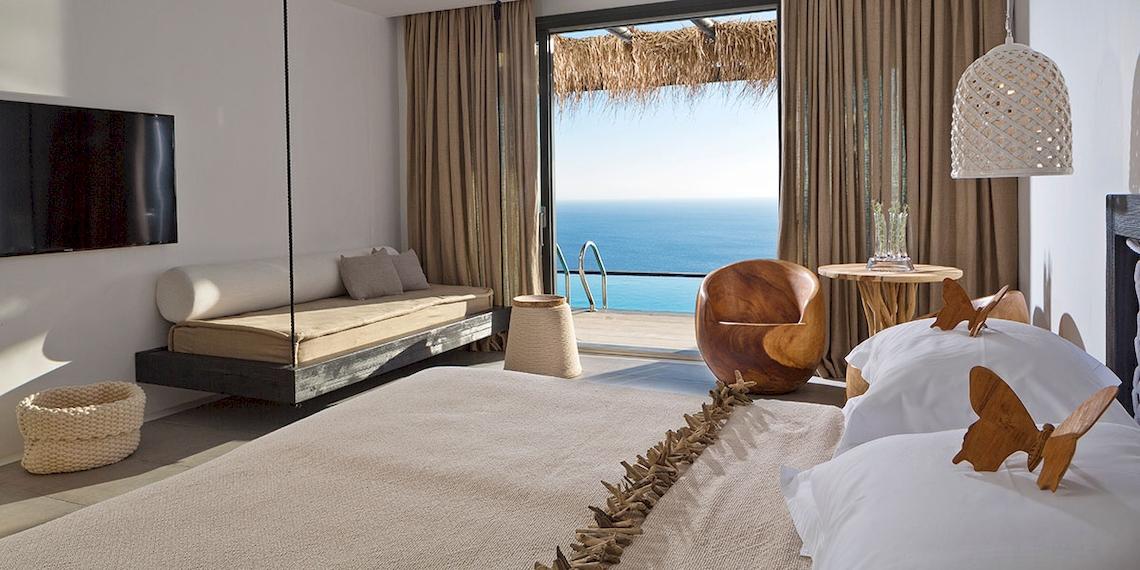 Luxus Schlafzimmer mit Meerblick im Myconian Utopia Resort, inklusive Bett, Sofa, Tisch und Fernseher.