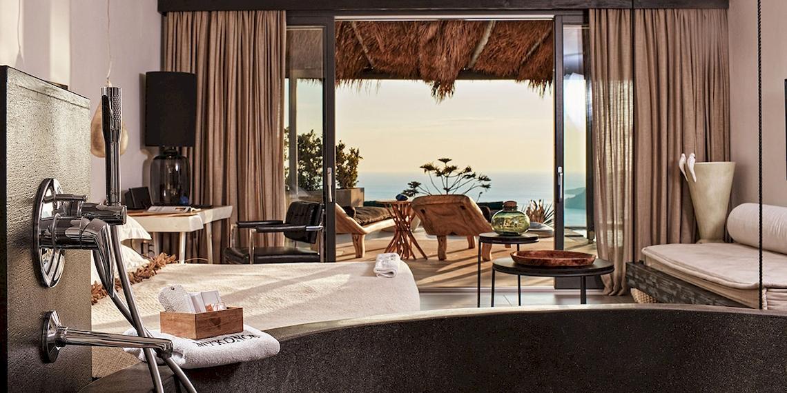 Hotelzimmer im Myconian Utopia Resort mit Aussicht auf den Ozean und einem großen Bett.