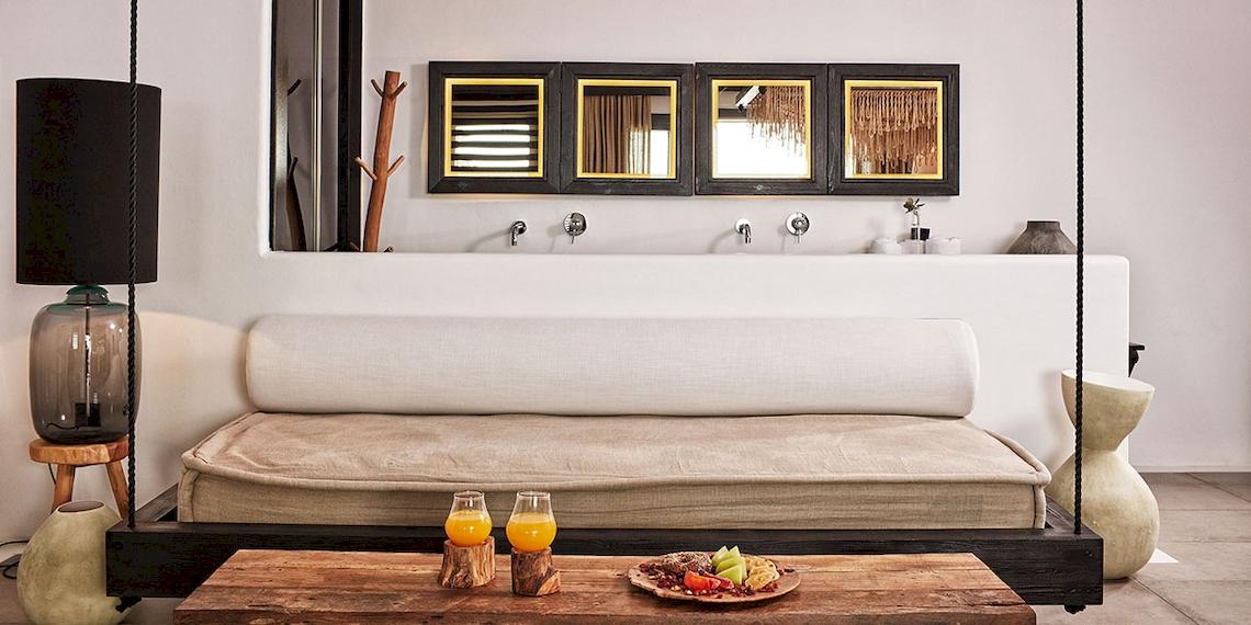 Innenansicht des Myconian Utopia Resorts mit Bett, Lampen und Tisch.