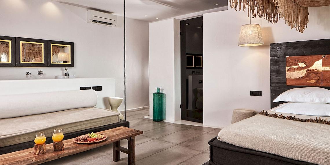 Innenansicht des Myconian Utopia Resorts mit Bett, Couch, Tisch und Dekorationen