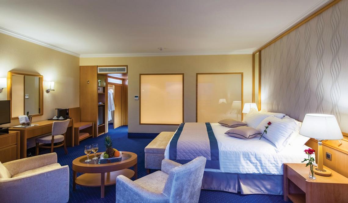 Zimmer im Athena Royal Beach Hotel mit einem Bett und Sitzgelegenheiten.
