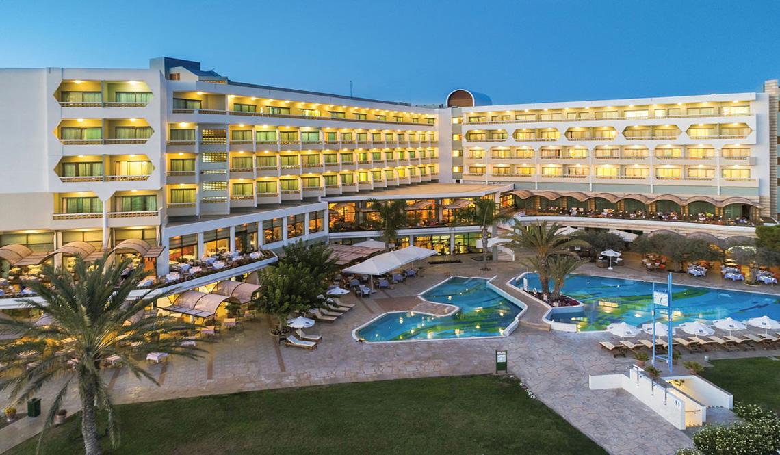 Außenansicht des Athena Royal Beach Hotel mit Swimmingpool und Loungebereichen.