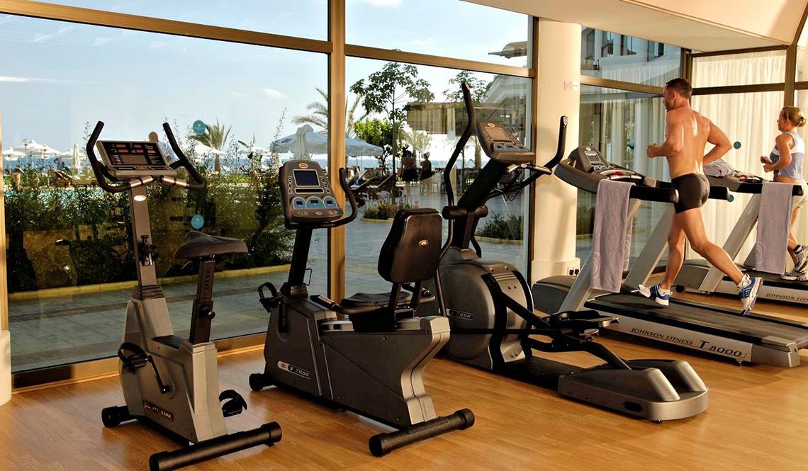 Fitness Center im Athena Royal Beach Hotel mit Laufband und anderen Geräten.