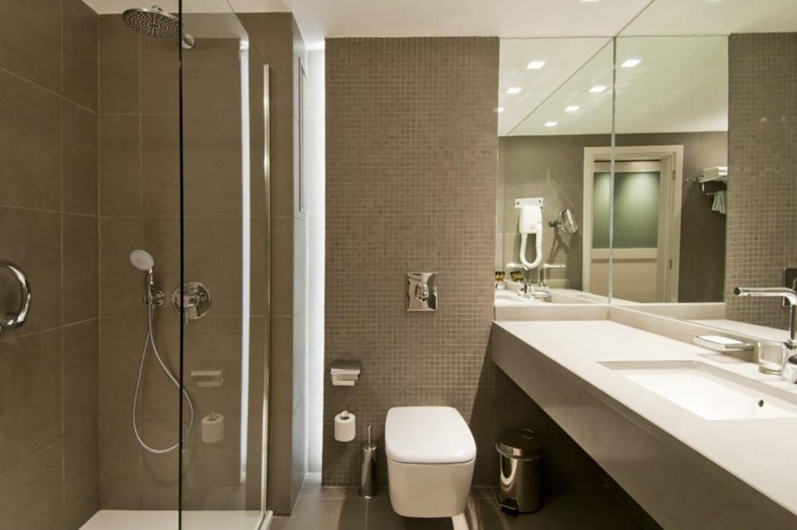 Badezimmer im Platanista Hotel mit Dusche, Toilette und Waschbecken.