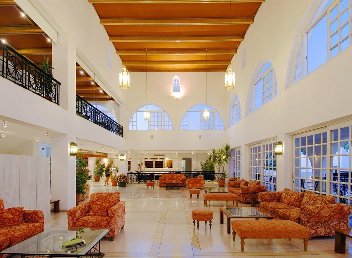Lobby des Platanista Hotels mit großen Fenstern, Holzdecken und orangefarbenen Möbeln.