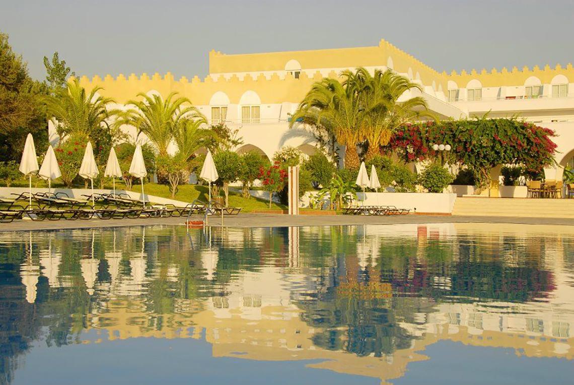 Außenbereich des Platanista Hotels mit Swimmingpool, Liegestühlen, Sonnenschirmen und Gebäude