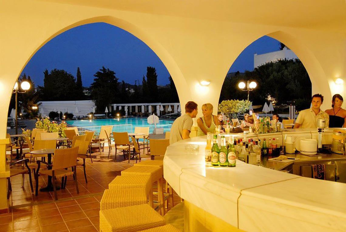 Terrasse im Platanista Hotel bei Nacht mit Pool und Gästen an der Bar.