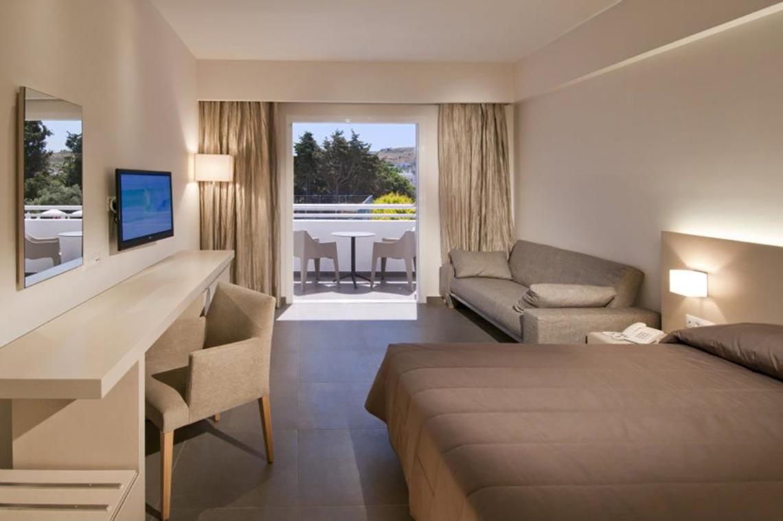 Innenansicht eines Zimmers im Platanista Hotel mit Bett, Schreibtisch, Fernseher und Balkon.