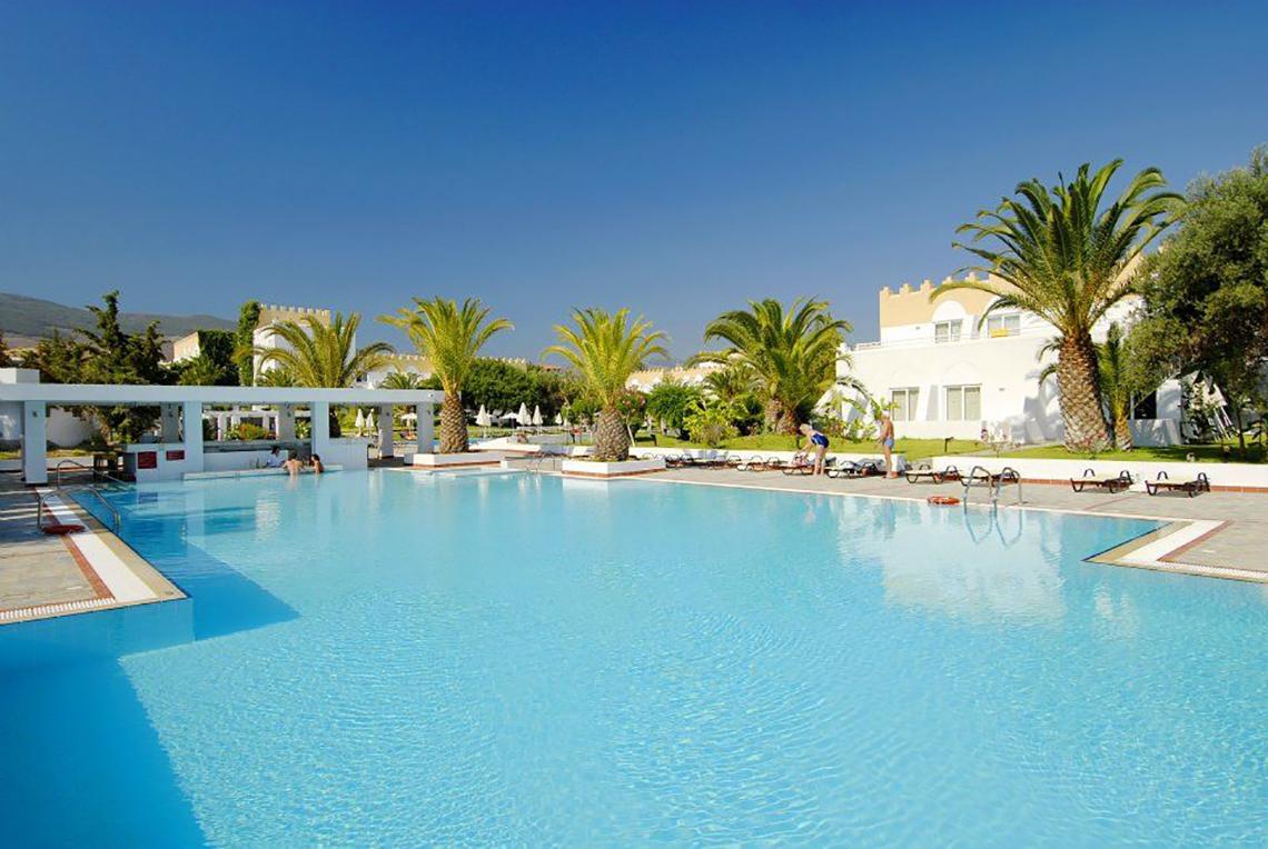 Außenpool des Platanista Hotels mit Sonnenliegen und Palmen im Hintergrund.