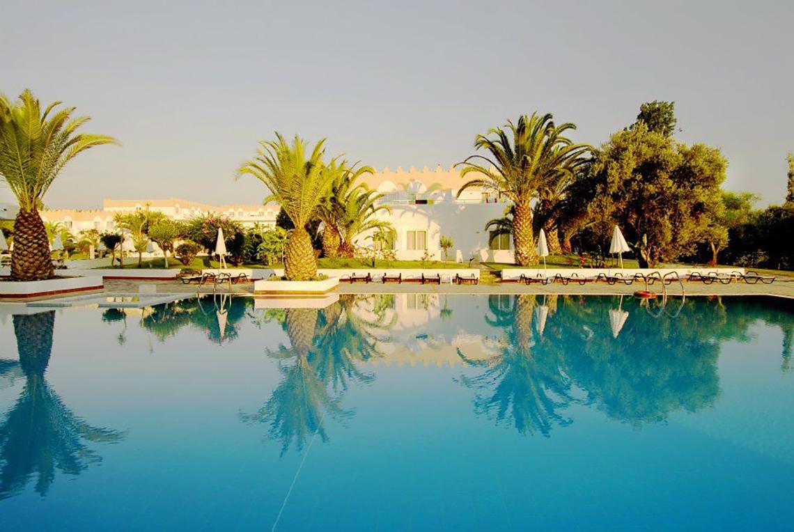 Außenpool des Platanista Hotels mit Loungeliegen und Palmen im Hintergrund.