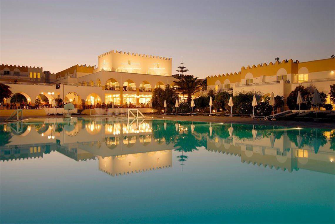 Das Platanista Hotel mit beleuchtetem Swimmingpool bei Nacht.