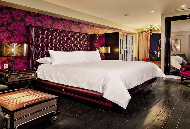 Schlafzimmer im Cromwell Las Vegas Hotel mit einem großen Bett, rotem Kopfteil und gemusterten Wänden.