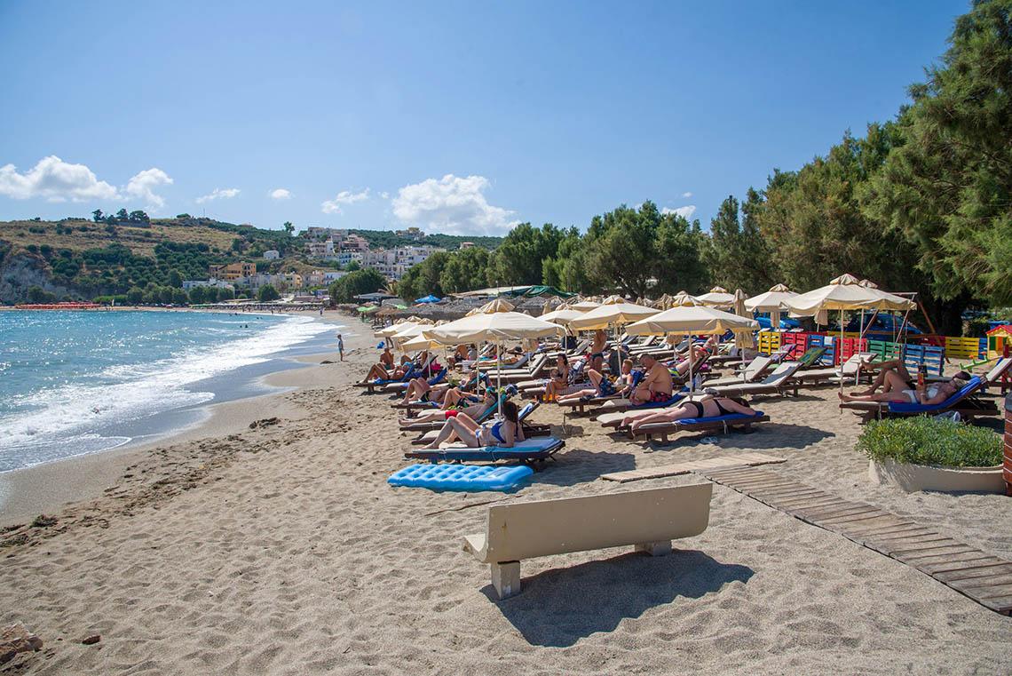 Strandszene mit Sonnenliegen und Gästen im Kalyves Beach Hotel.