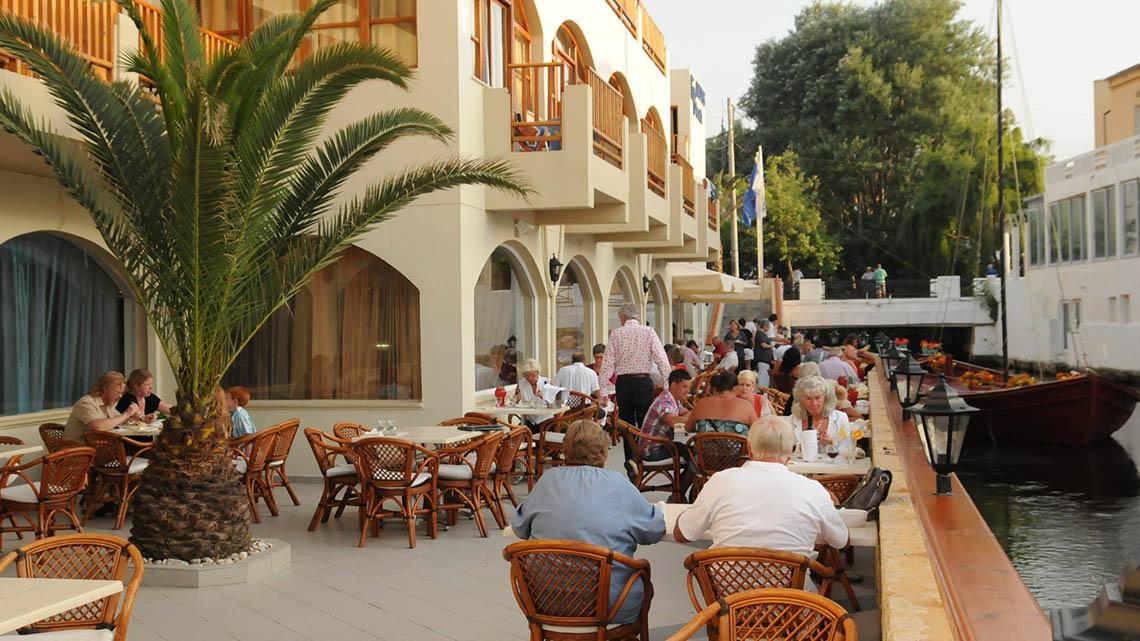 Gäste sitzen an Tischen auf der Terrasse des Kalyves Beach Hotels.