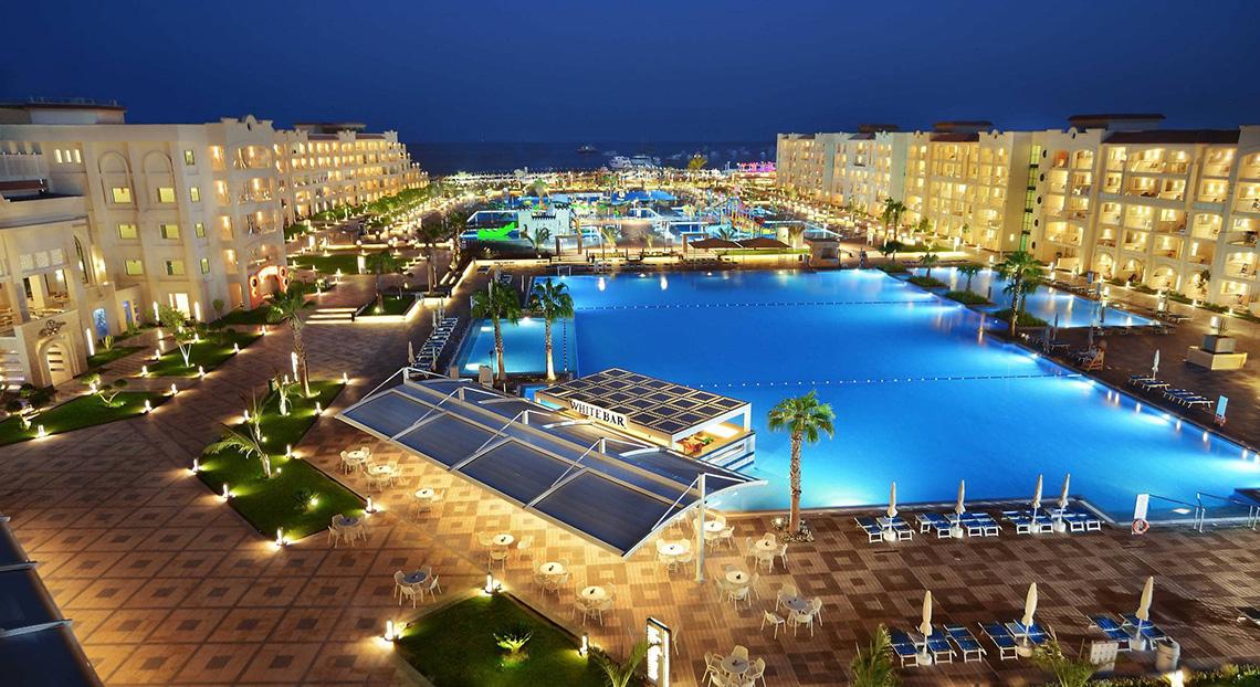 Nachtansicht des Pickalbatros White Beach Resorts mit großem Pool und beleuchteten Gebäuden.