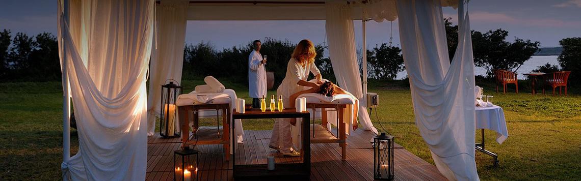 Spa-Massage auf der Terrasse im Coral Beach Hotel & Resorts mit zwei Frauen, weiße Vorhänge und Kerzen.