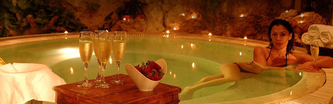 Eine Frau genießt ein Getränk in einem beleuchteten Whirlpool mit Champagner und Erdbeeren.