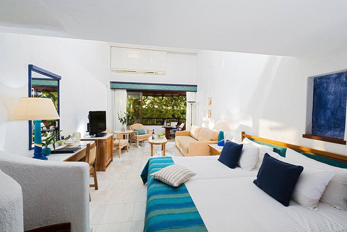 Suite-Zimmer im Coral Beach Hotel & Resorts mit Balkon, Bett, Sofa und Tisch.