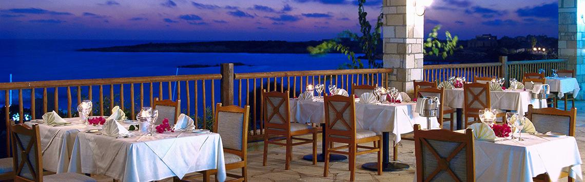 Außenterrasse des Coral Beach Hotel & Resorts mit Blick auf das Meer am Abend.