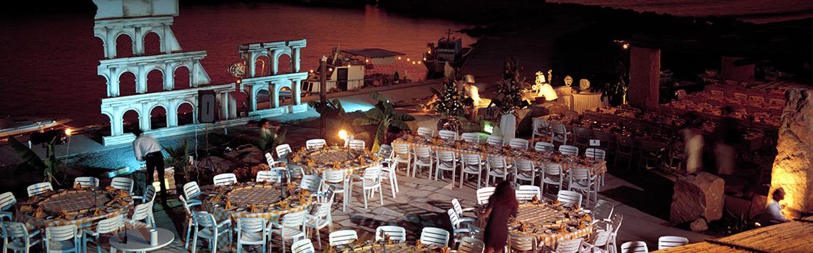 Abendessen am Pool im Coral Beach Hotel & Resorts mit vielen runden Tischen und Stühlen, umgeben von Dekoration.