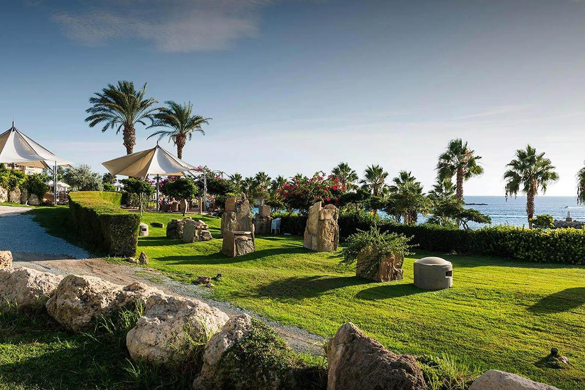 Außenbereich des Coral Beach Hotel & Resorts mit Palmen und Blick auf das Meer