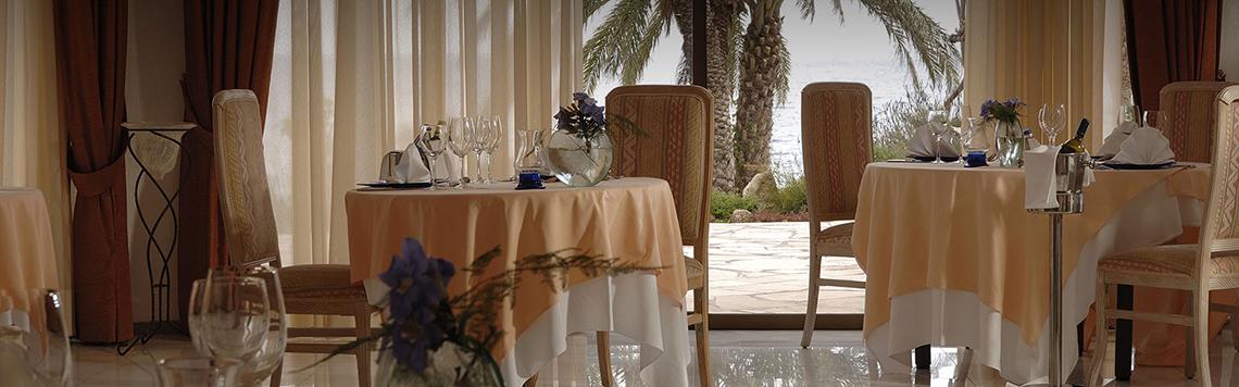 Innenansicht eines elegant eingerichteten Restaurants im Coral Beach Hotel mit Blick auf das Meer.
