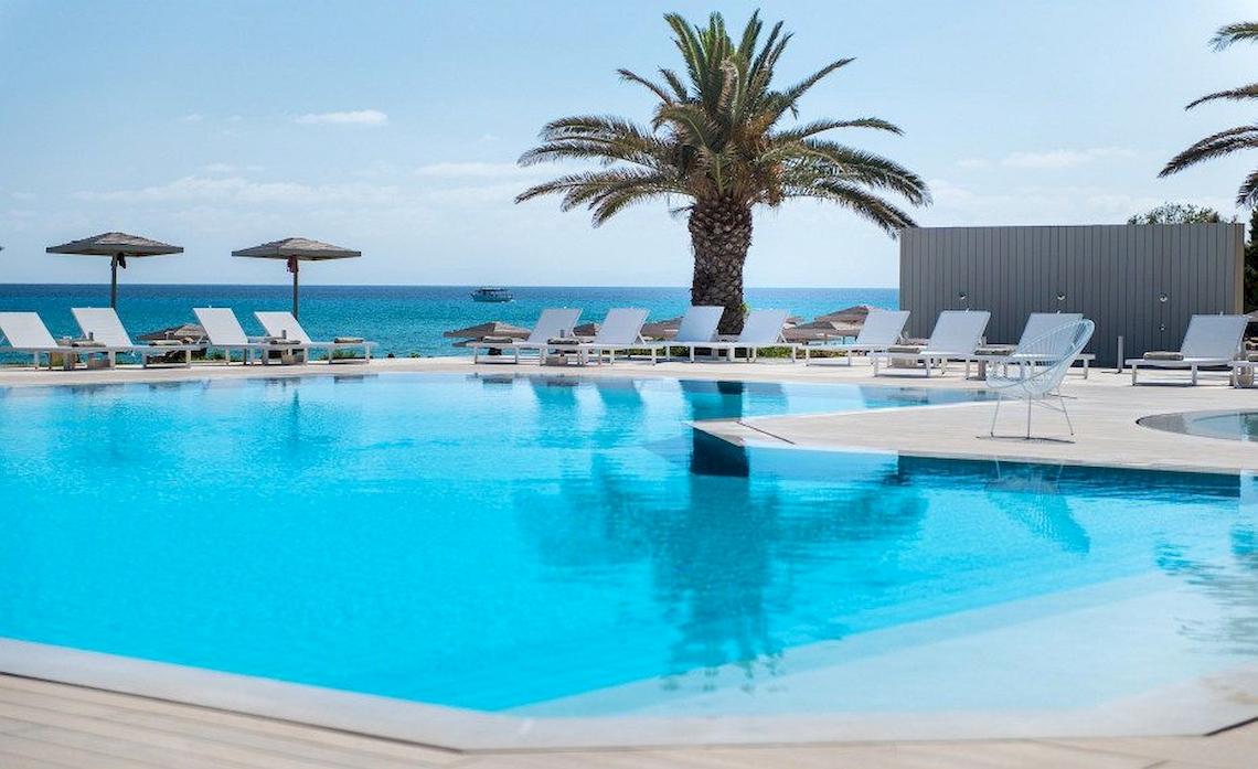 Der Pool des Bay Hotels mit Liegestühlen und Sonnenschirmen am Meer