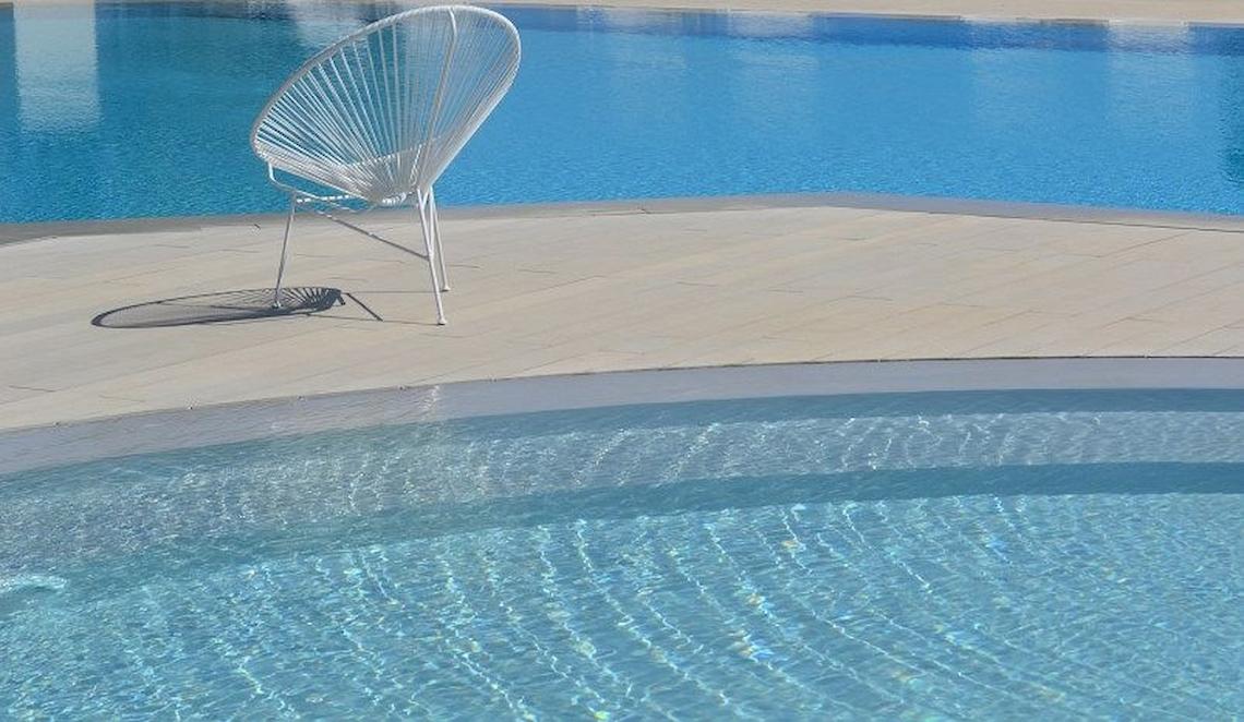 Außenpool des Bay Hotel & Suites mit einem weißen Stuhl neben dem Rand