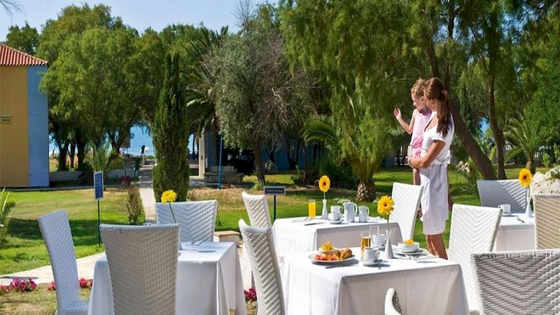 Zwei Frauen stehen vor einem Frühstückstisch im Freien im Garten des Bay Hotel & Suites.