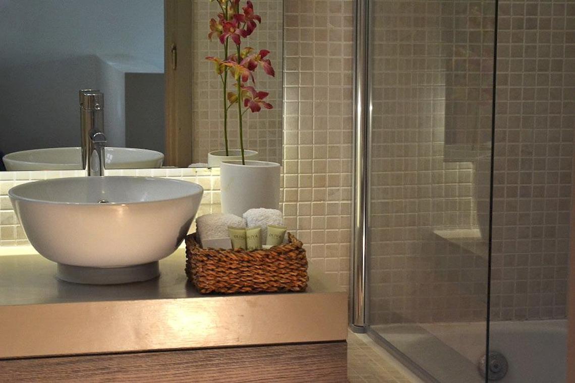 Das Badezimmer im Bay Hotel & Suites mit einem Waschbecken, Handtüchern und einem Korb mit Pflegeprodukten.