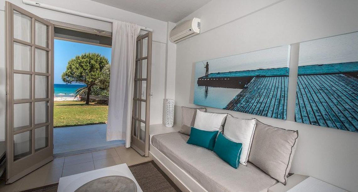 Wohnzimmer mit Meerblick im Bay Hotel & Suites, mit offenem Balkon und großer Fensterfront.