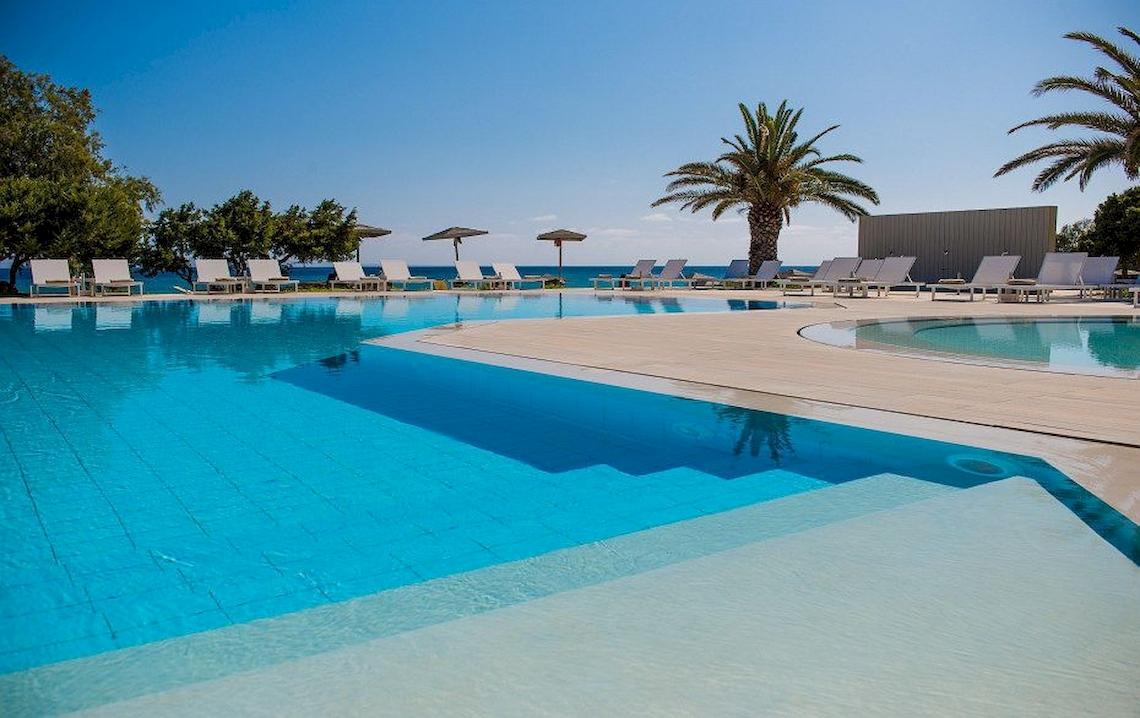 Außenpool des Bay Hotel & Suites mit Sonnenliegen und Sonnenschirmen.