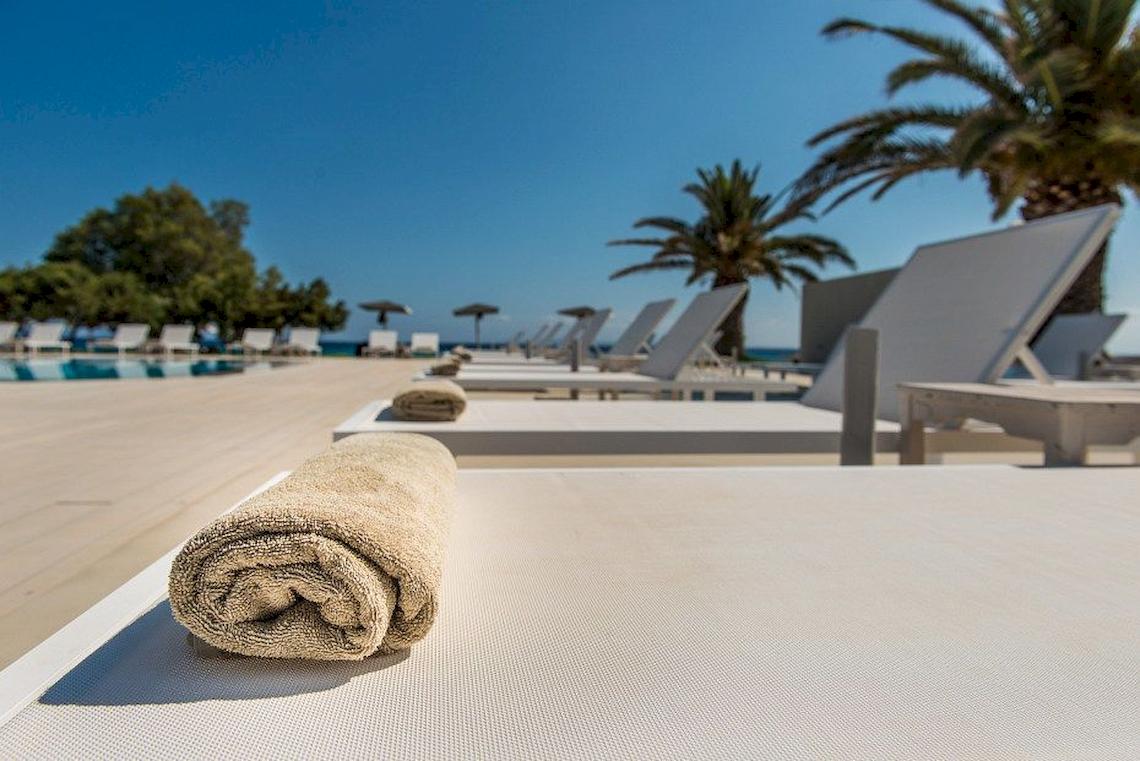 Einige Liegestühle am Pool des Bay Hotel & Suites mit Handtüchern