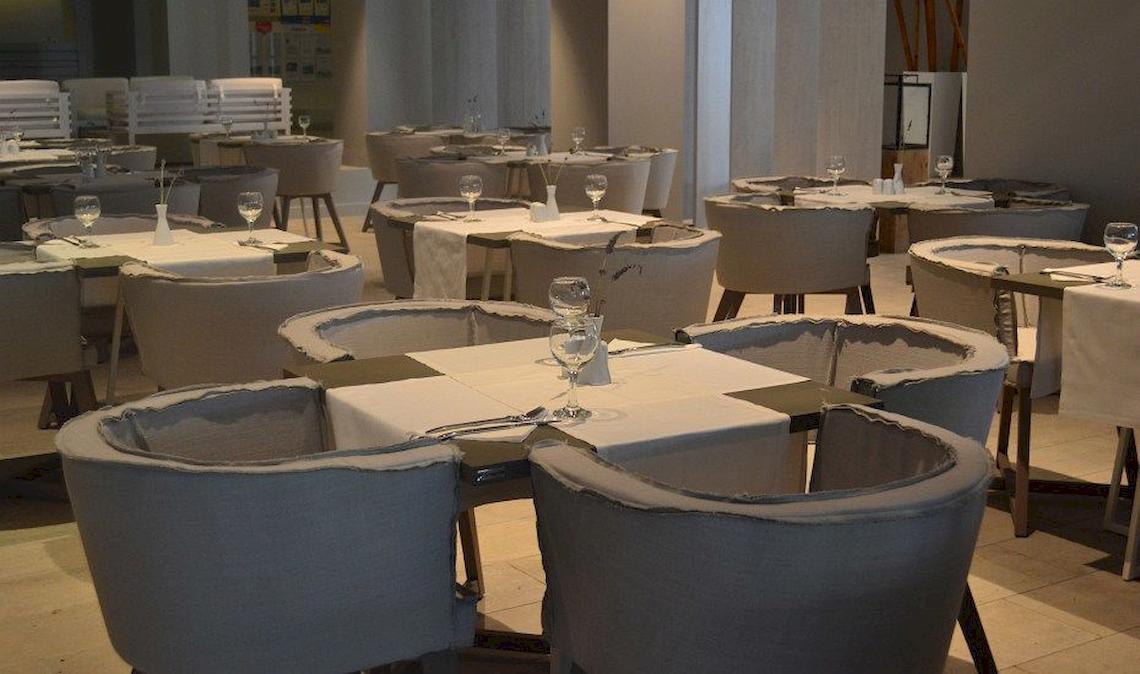 Innenansicht des Restaurants im Bay Hotel & Suites mit gedeckten Tischen und Stühlen.