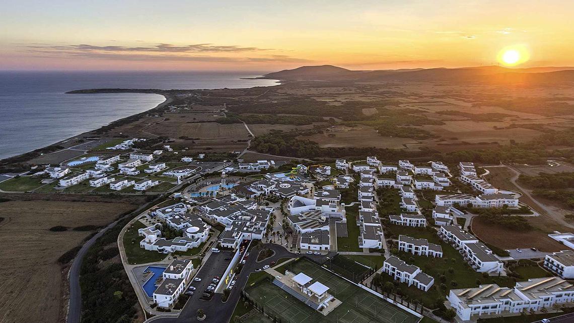 Sonnenuntergang über der Bucht des Club Plimmiri Hotels mit Blick auf das Meer und die umliegenden Gebäude.